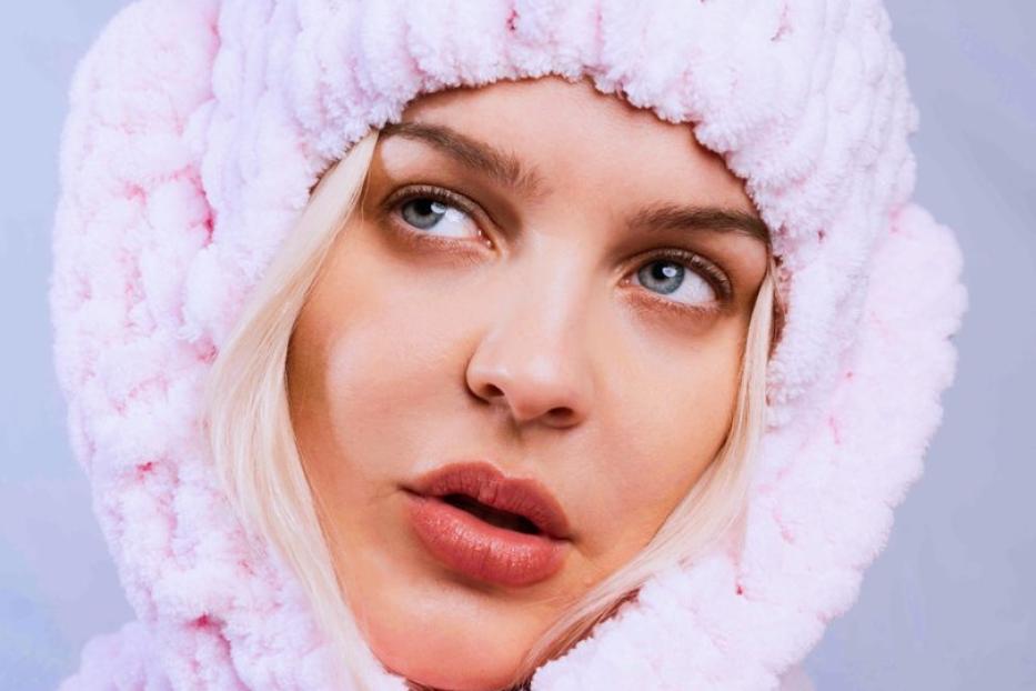 Die Sängerin Anne-Marie trägt eine flauschige, rosa Mütze und einen Schal.