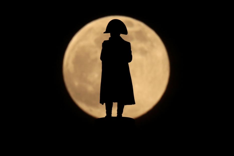 Die Silhouette einer Napoleon-Statue vor einem Vollmond.