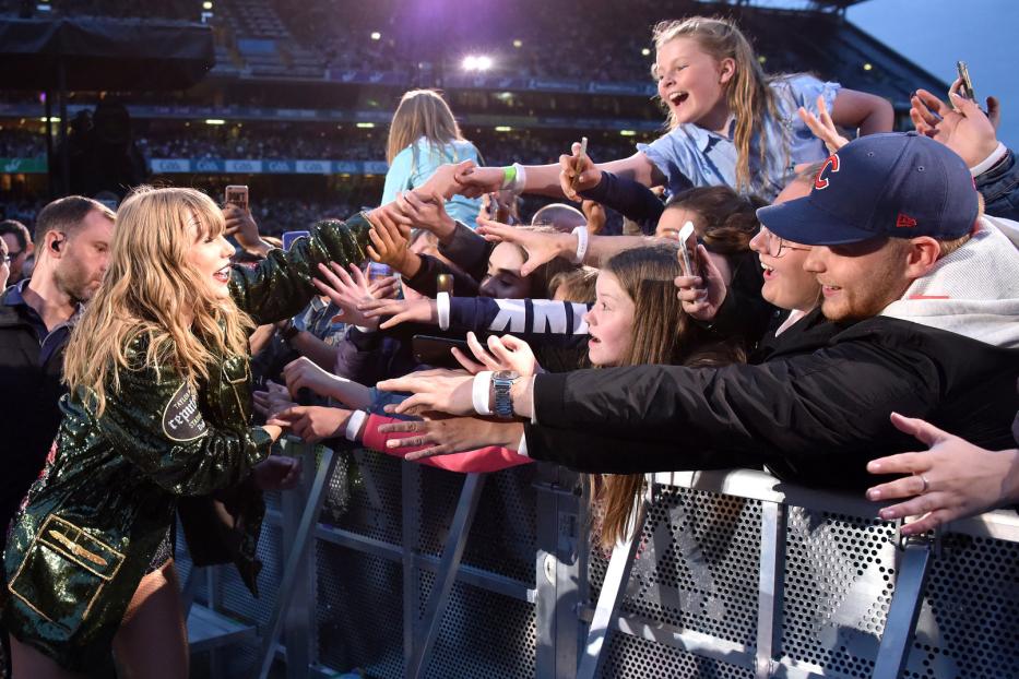 Taylor Swift interagiert während eines Konzerts mit Fans an der Absperrung.
