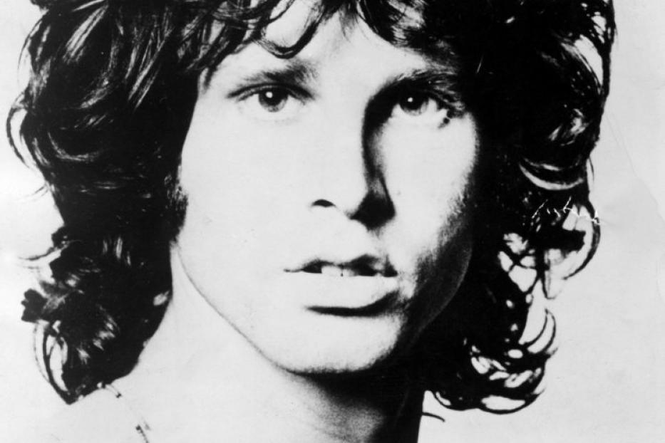 Ein Schwarz-Weiß-Porträt von Jim Morrison mit lockigem Haar und einer Halskette.