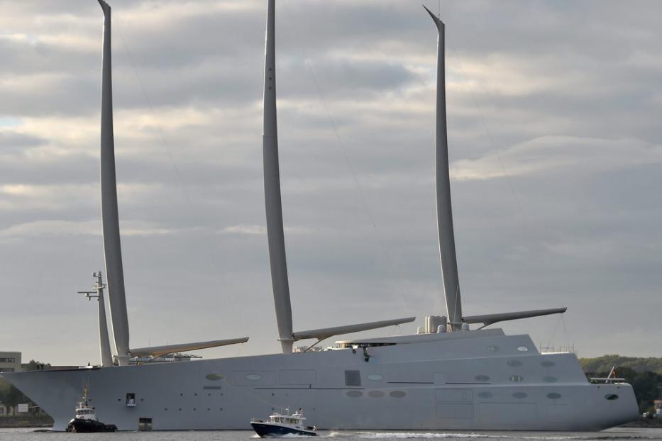 Eine große Segelyacht mit drei Masten wird von zwei Schleppern gezogen.