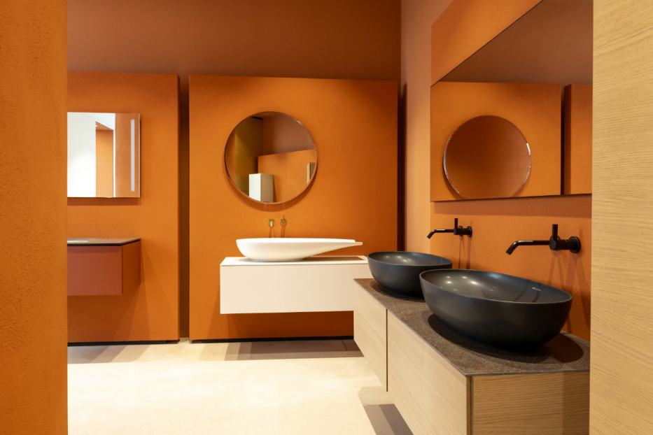 Ein Badezimmer in Orange mit mehreren Waschbecken und Spiegeln.