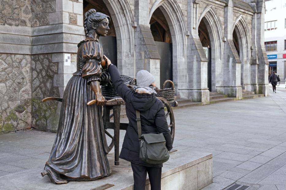 Eine Touristin berührt die Brust der Molly-Malone-Statue.