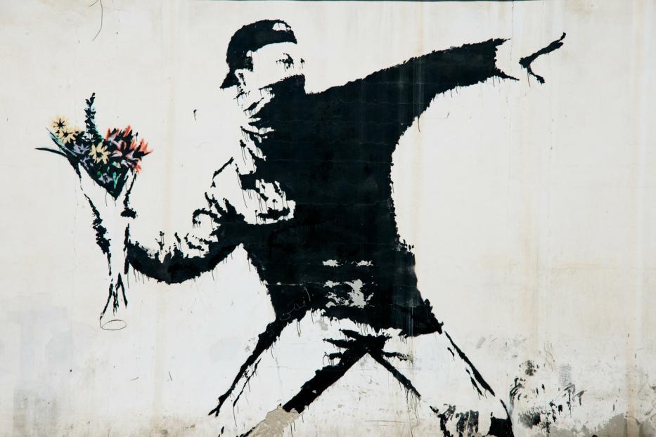 Ein Banksy-Graffiti zeigt eine Person, die statt eines Molotowcocktails einen Blumenstrauß wirft.