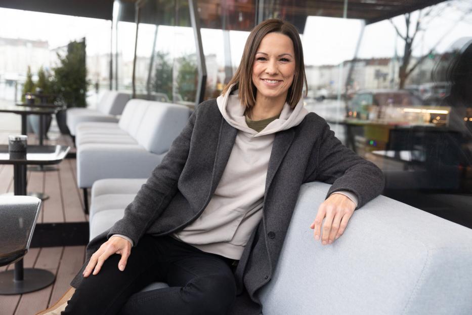 Christina Stürmer sitzt lächelnd auf einem Sofa.
