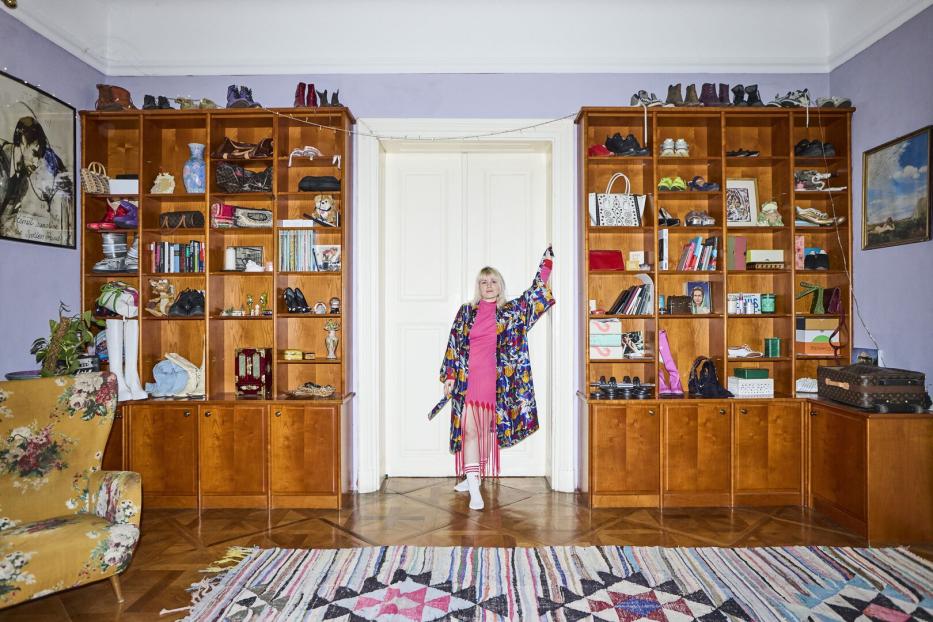 Eine Frau in einem bunten Kimono steht in einem Raum mit vollen Bücherregalen.