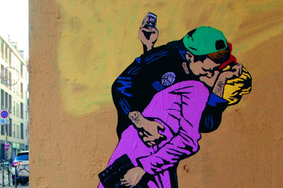 Ein Banksy-Graffiti zeigt zwei sich küssende Polizisten, von denen einer ein Handy hält.