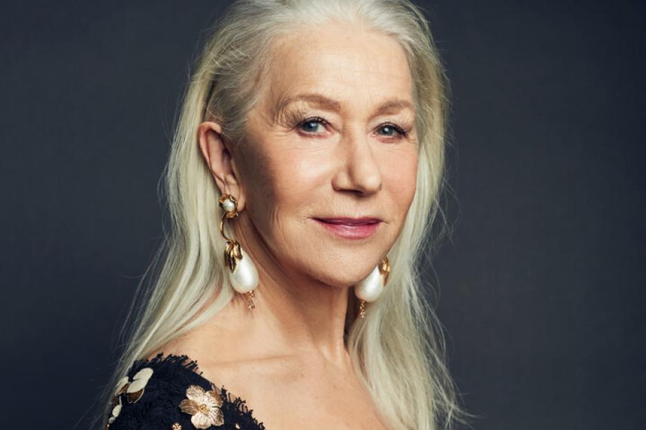 Helen Mirren trägt ein schwarzes Kleid mit goldenen Blumen und auffällige Ohrringe.