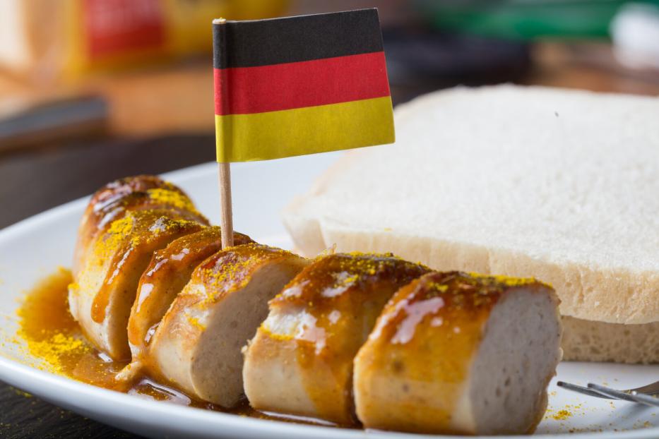 Auf einer Currywurst steckt eine Papierflagge mit den deutschen Farben Schwarz, Rot, Gold.