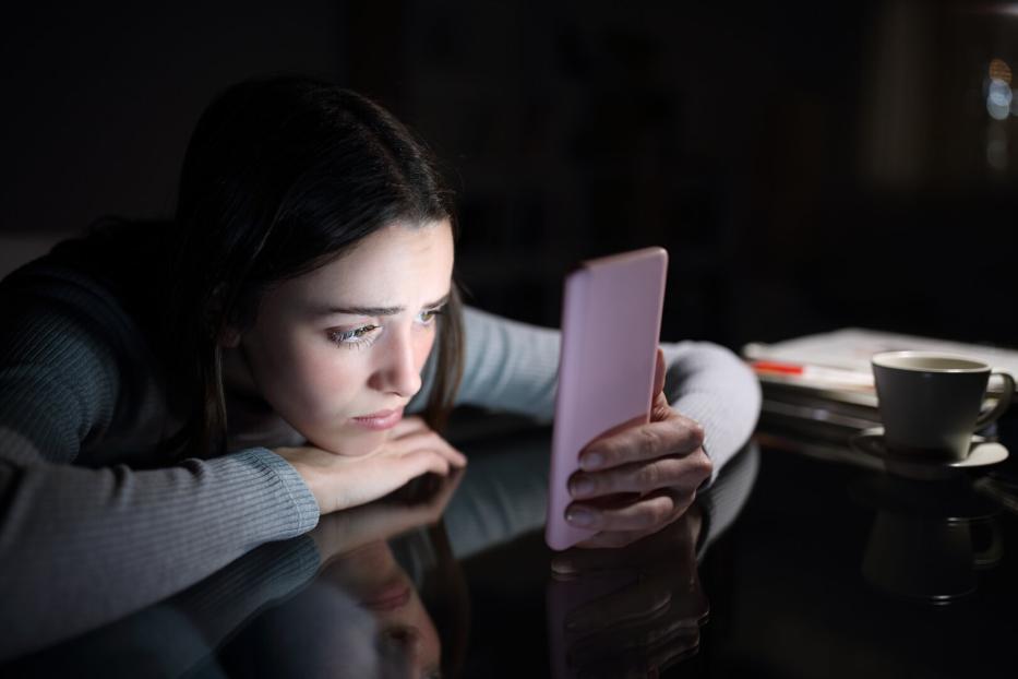 Frau schaut traurig auf ihr Smartphone.