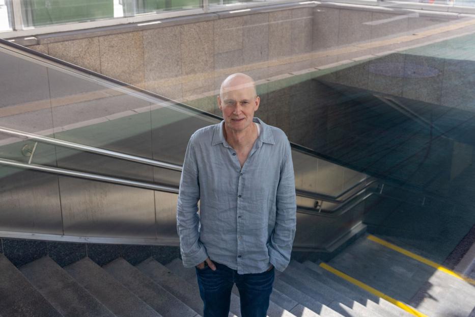 Arno Geiger steht vor einer Treppe.