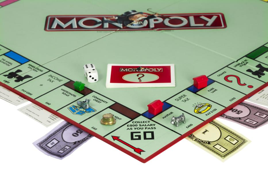 Ein Monopoly-Spielbrett mit Spielfiguren, Häusern und Spielkarten.