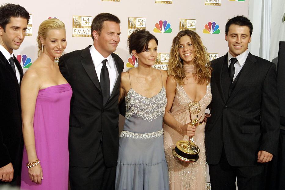 Die Besetzung von „Friends“ posiert mit Jennifer Aniston, die eine Emmy-Trophäe hält.