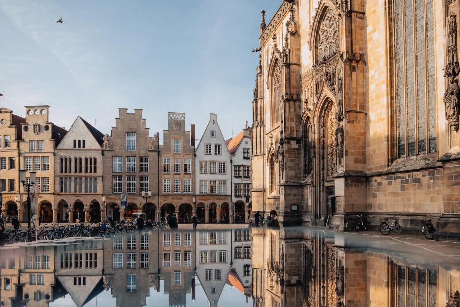 Der Prinzipalmarkt und die Lambertikirche in Münster spiegeln sich im Wasser.