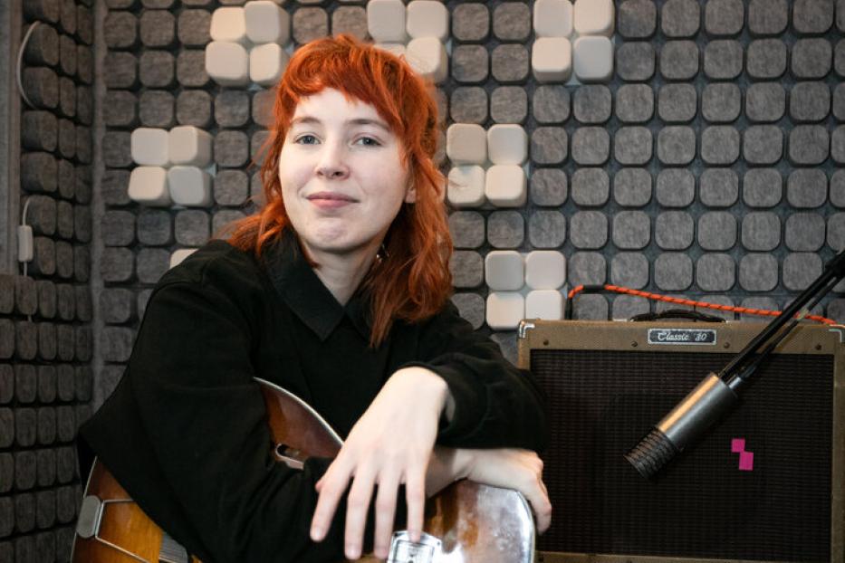 Mira Lu Kovacs mit Gitarre in einem Aufnahmestudio.