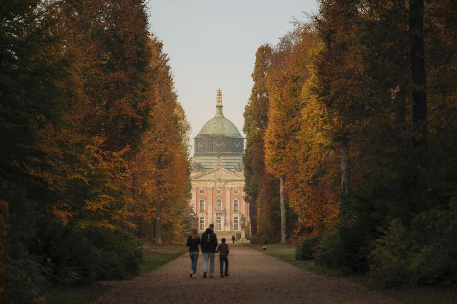 Ein Paar genießt einen Spaziergang mit ihrem Hund auf einem ruhigen Weg in der Natur. Am Ende des Weges steht ein Schloss.
