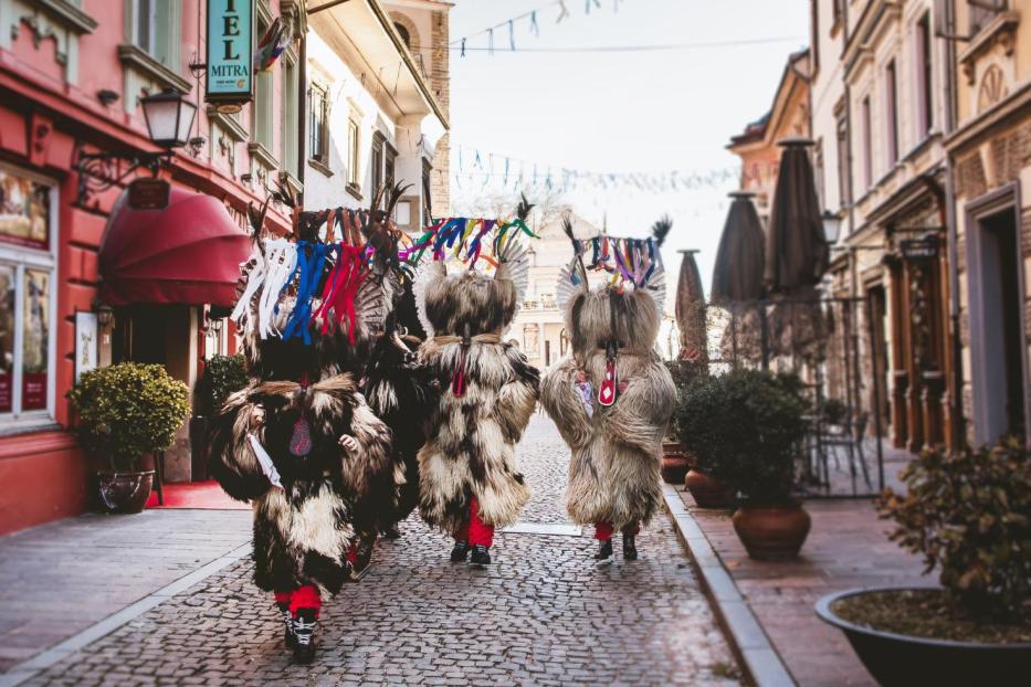 Kurenti, traditionelle slowenische Karnevalsfiguren, ziehen durch eine Stadtstraße.