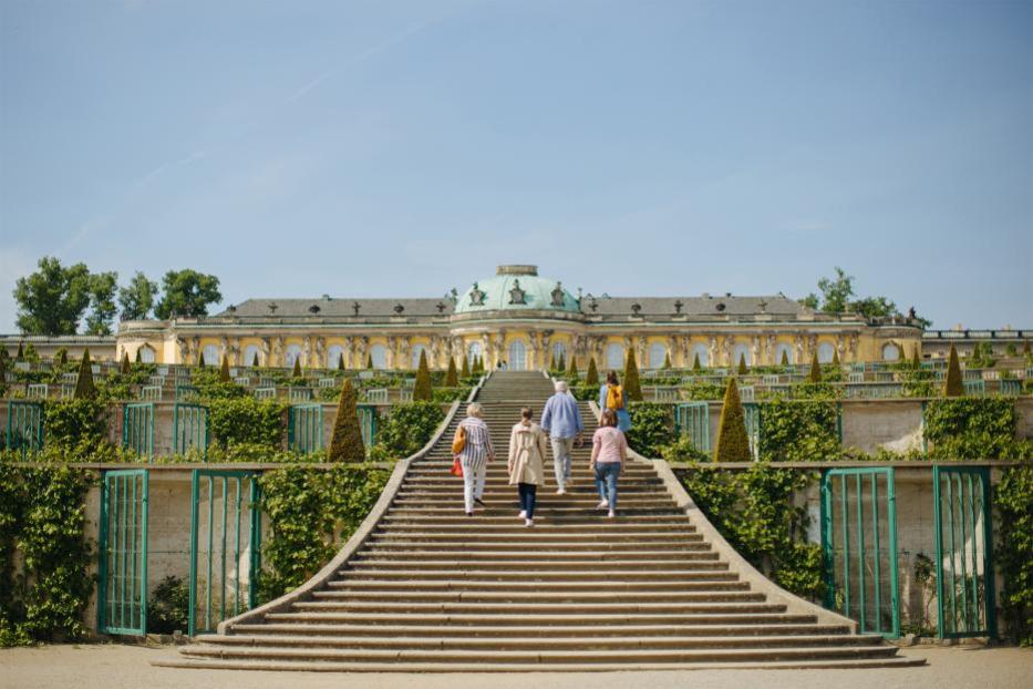 Besucher steigen die Treppe zum Schloss Sanssouci in Potsdam hinauf.