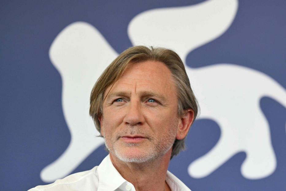 Porträt von Daniel Craig vor einem blauen Hintergrund mit weißem Logo.