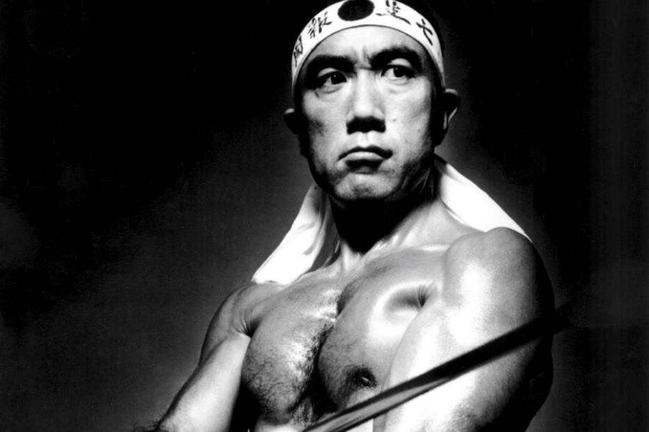 Yukio Mishima in der Rolle eines idealisierten japanischen Kriegers, der das Stirnband eines Kamikaze trägt und ein Schwert schwingt.