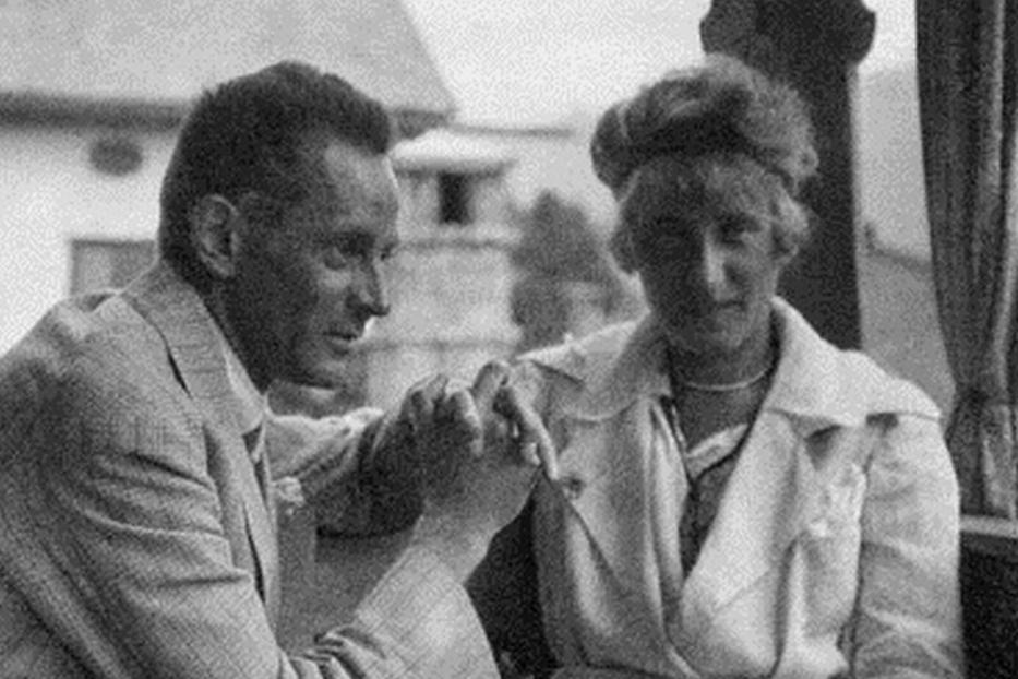 Ein Mann und eine Frau halten Hände, möglicherweise vor einem Haus.