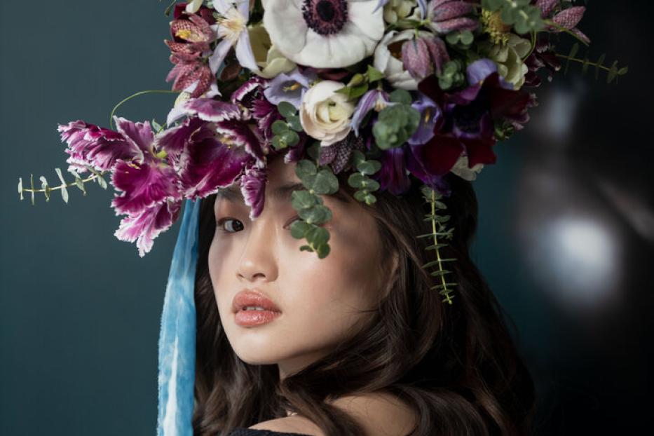 Eine Frau mit einem großen Blumenkopfschmuck aus weißen und violetten Blumen.