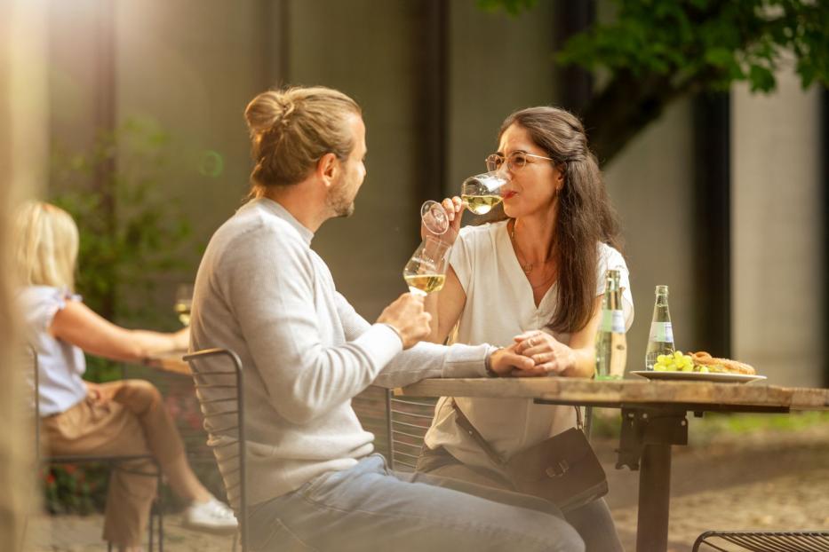 Ein Paar sitzt im Freien und genießt ein Glas Weißwein.