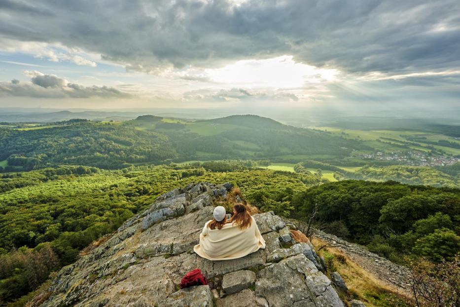 Zwei Wanderinnen, die den Sonnenuntergang am Berg Milseburg in Hofbieber betrachten.