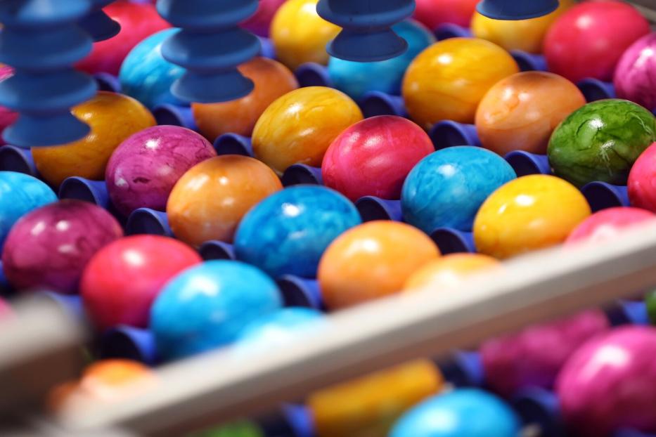 Bunte Ostereier liegen in einer Sortiermaschine.