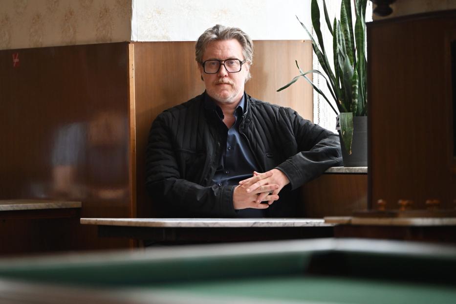 Ein Mann mit Brille sitzt an einem Tisch in einem Café.