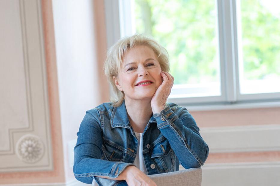 Eine Frau in Jeansjacke und Tüllrock sitzt auf einem Stuhl.