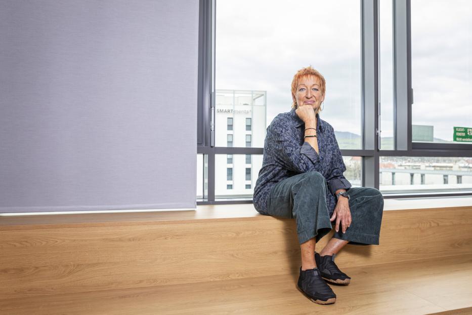 Eva Rossmann sitzt vor einem Fenster in einem Büro.