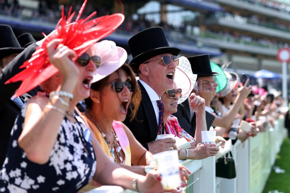 Besucher in Hüten und Anzügen jubeln auf der Pferderennbahn Royal Ascot.