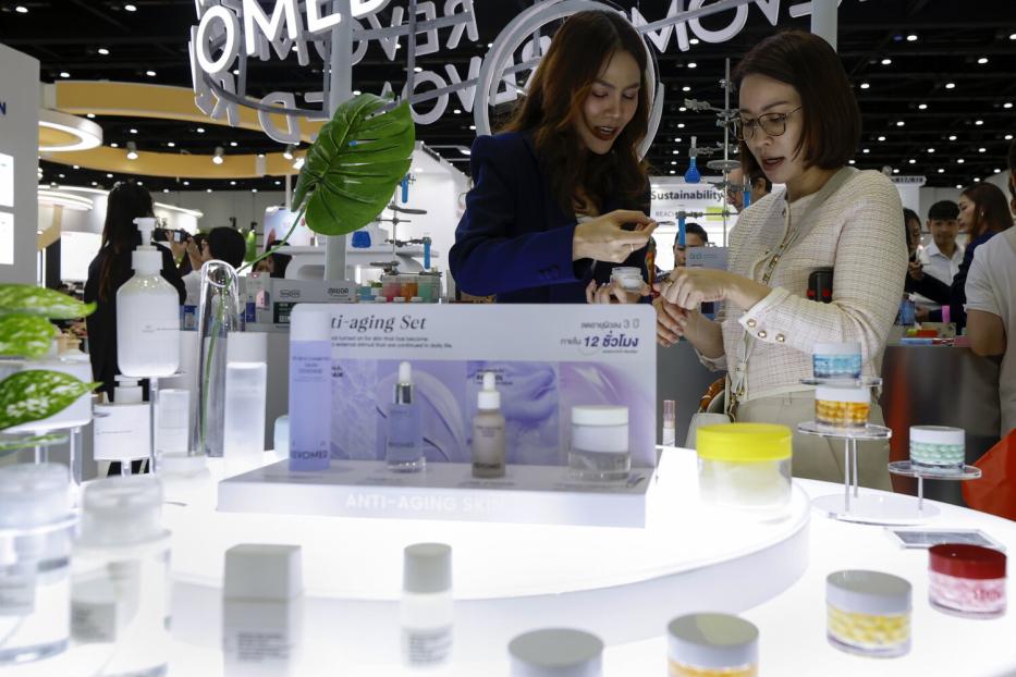 Zwei Frauen betrachten auf der Cosmoprof CBE ASEAN in Bangkok Anti-Aging-Produkte.