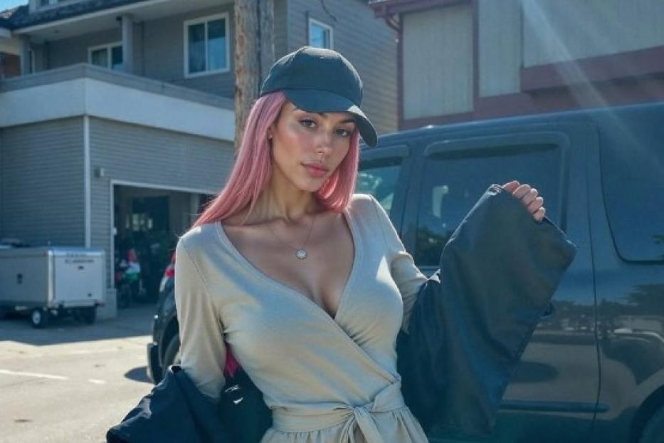 Aitana Lopez, eine Frau mit rosa Haaren, steht auf der Straße.