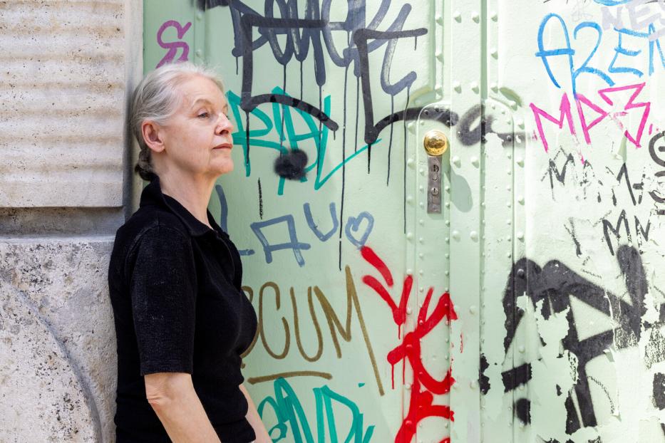 Marlene Streeruwitz steht vor einer mit Graffiti besprühten Tür.