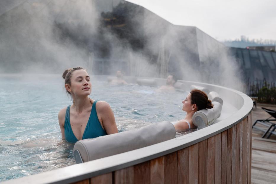 Eine Frau sitzt im Whirlpool und hat ihre Augen geschlossen.