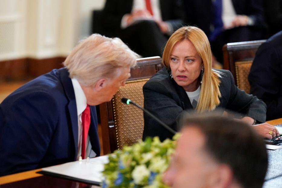 Donald Trump sitzt neben Giorgia Meloni vor einem Mikro.