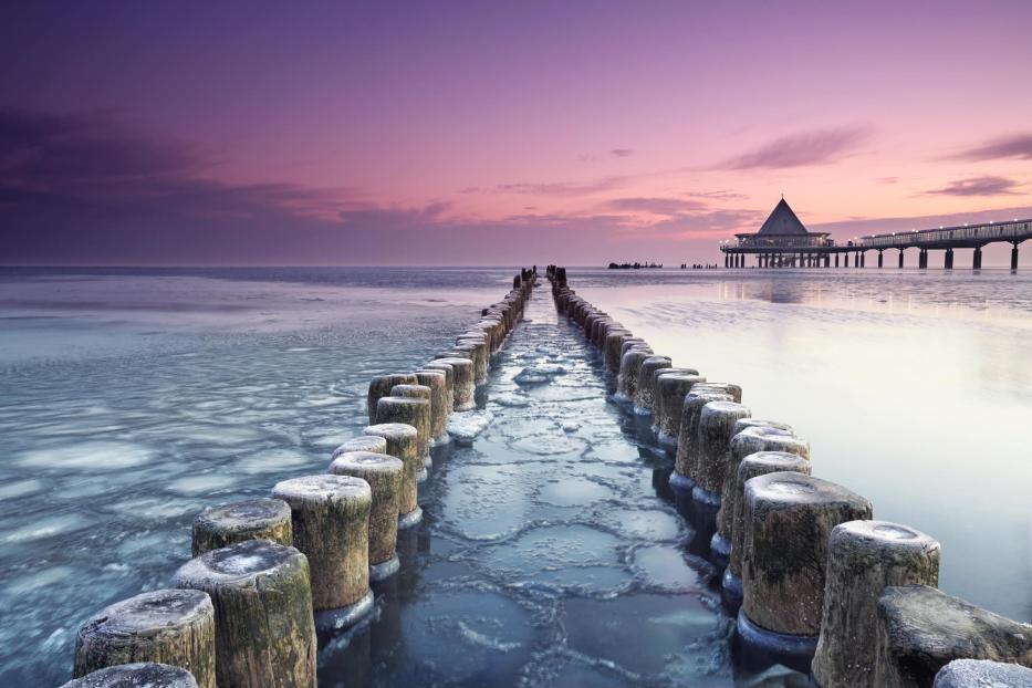 Ein Sonnenuntergang an einem Meer; mit Holzpfosten, die ins Wasser gehen