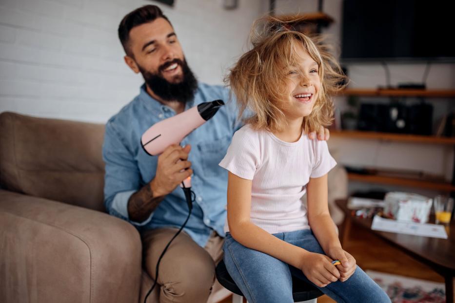 Father drying his cute little daughter's hair with blowdryer