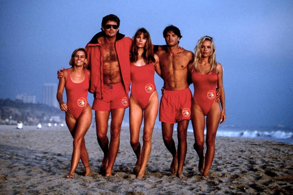 Die Rettungschwimmer aus den Neunzigern am Strand - sie haben sich ihre Arme um die Schultern gelegt.