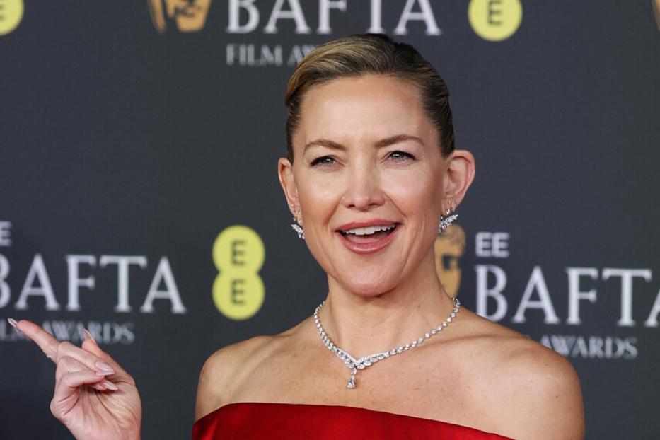 Kate Hudson in einem roten, schulterfreien Kleid und Schmuck auf dem roten Teppich der BAFTA Film Awards.