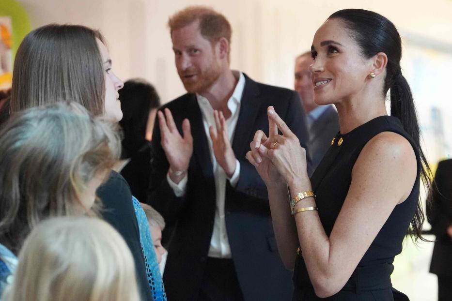 Meghan bei einem Besuch in Melbourne im Gespräch mit Gästen, dahinter Harry