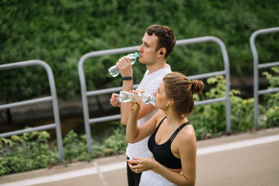 Zwei junge Menschen trinken während des Sports Wasser im Freien.