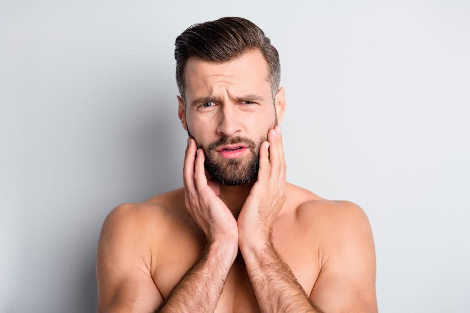 Photo of young handsome man unhappy sad upset displeased problem hand touch beard isolated over grey color background