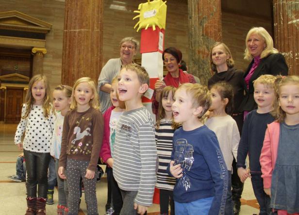 Eine Gruppe Kinder steht vor Säulen und singt.