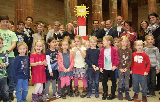 Eine Gruppe von Kindern und Erwachsenen posiert vor einem selbstgebastelten Leuchtturm.