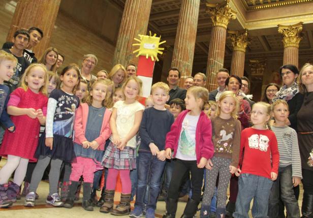 Eine Gruppe von Kindern und Erwachsenen posiert vor Säulen für ein Foto.