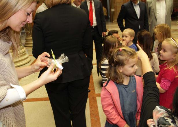Eine Frau verteilt kleine Geschenke an eine Gruppe von Kindern.