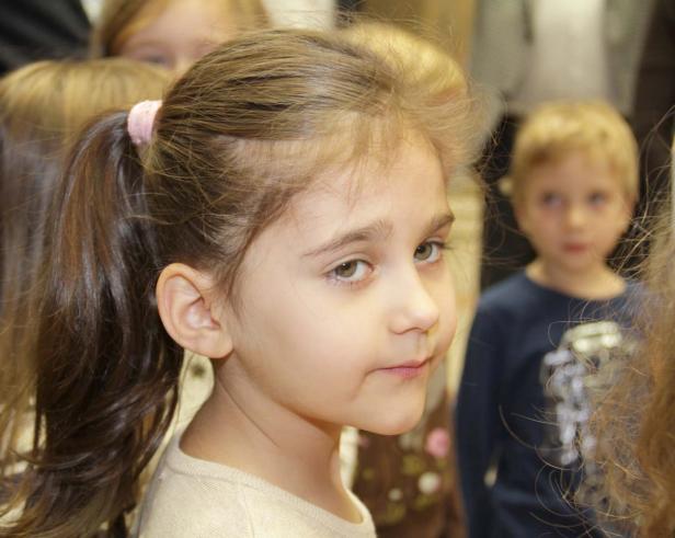 Ein junges Mädchen mit braunen Haaren und einem Pferdeschwanz schaut zur Seite.